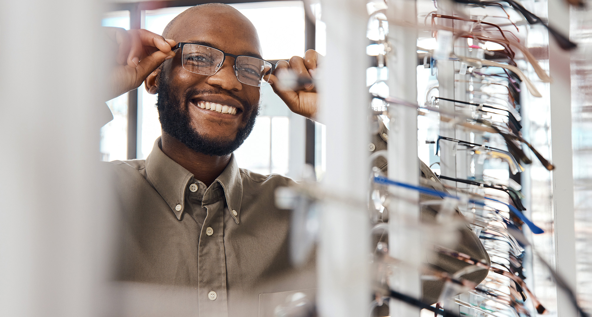 fotografie a unei persoane zâmbitoare încercând ochelari la optician