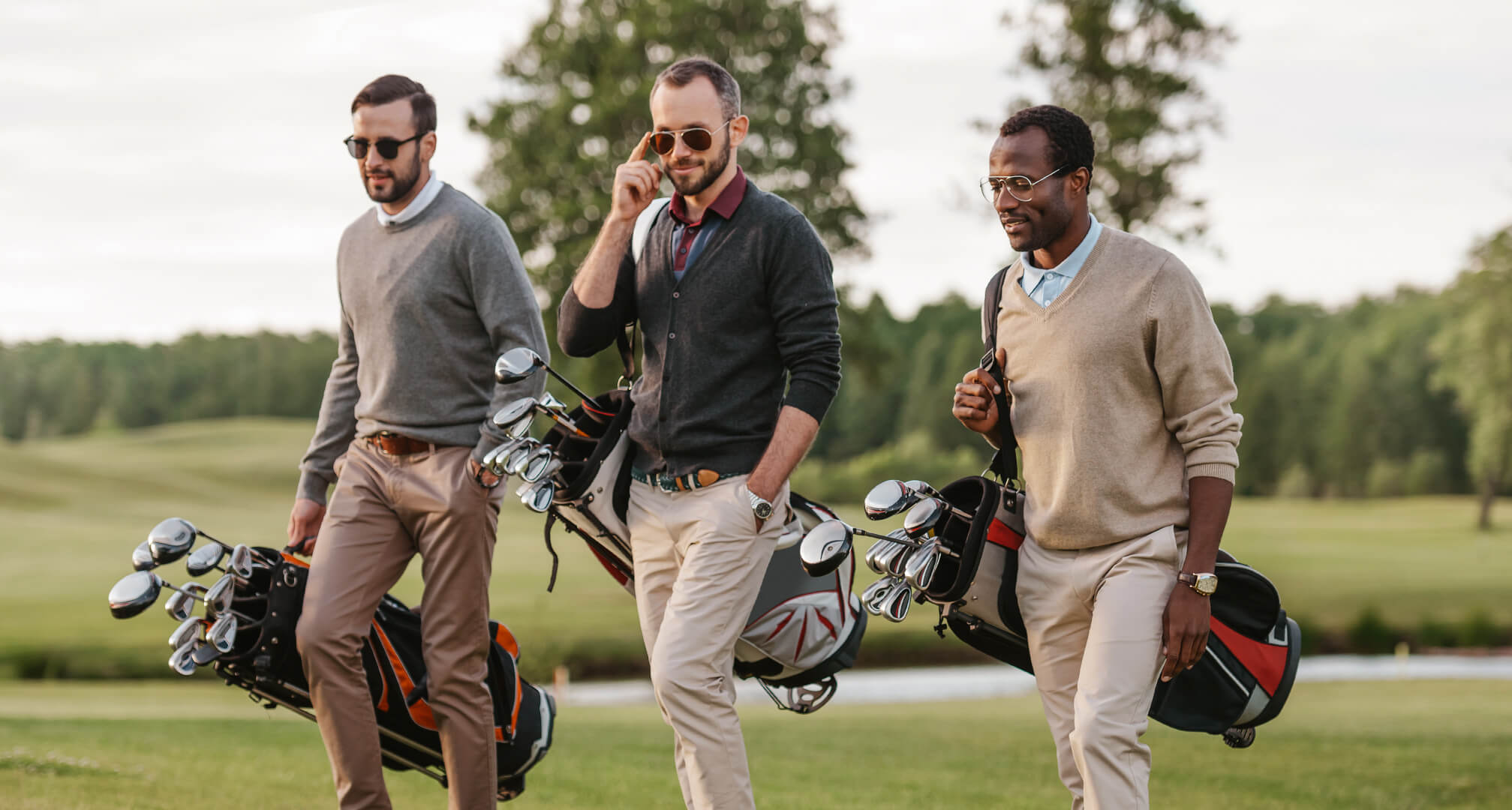 trei oameni care joacă golf cu ochelari de soare și saci de golf