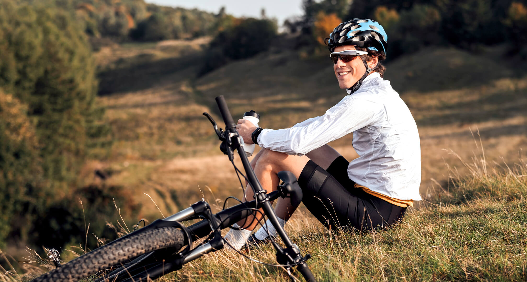 persoană care stă pe deal cu bicicleta de munte și poartă ochelari de soare